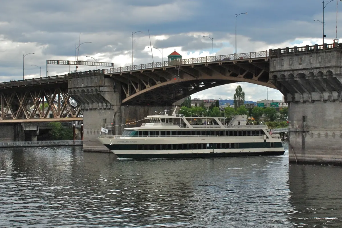 Um barco da Portland Spirit Cruises a passar sob os arcos de betão e aço da Burnside Bridge